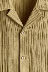 Camisa de manga corta H&M con cuello resort, cierre frontal de botones y bolsillos frontales aplicados. Confeccionada en tejido texturizado de corte relajado.