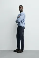 Pantalón chino de corte ajustado, color beige, con bolsillos laterales y bolsillos traseros de vivo. Cuenta con cierre frontal de cremallera y botón.