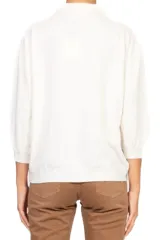 Polo de color blanco con cuello clásico, cierre frontal de botones y mangas largas con volumen abullonado.