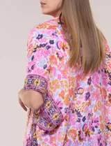 Kimono de gasa ligera con estampado floral en tonos rosados, anaranjados y violetas. Presenta diseño abierto al frente, mangas amplias tipo kimono y detalle de borlas en el ruedo asimétrico.