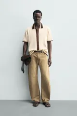 Camisa de punto de algodón con corte relajado, cuello solapa y manga corta. Presenta un diseño bicolor en tonos beige y marrón, con cierre frontal de botones.