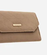 Billetera tipo sobre de tamaño mediano, confeccionada en material sintético efecto gamuza color tostado. Presenta un diseño acolchado con costuras diagonales y placa metálica dorada con el logo de la marca en la solapa frontal.