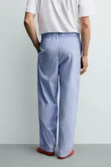 Set de pijama para hombre compuesto por una remera blanca de cuello redondo y mangas cortas, y un pantalón celeste a rayas verticales con cintura elástica y bolsillos laterales.