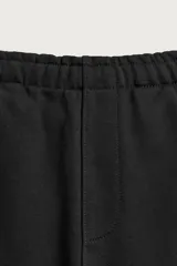 Pantalón jogger de corte regular fit y color negro, confeccionado en tejido compacto de algodón con interior de rizo. Cuenta con cintura elástica, bolsillos frontales y un bolsillo trasero de doble vivo.