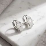 Caravanas de acero plateado con dije en forma de mano de Fátima, decorado con una incrustación central de nácar en forma de corazón.