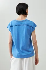 Remera color durazno con cuello en V y detalle de trenza en el escote.
