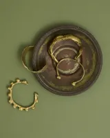Pulsera esclava abierta de diseño artesanal con acabado orgánico y texturizado, realizada en bronce.