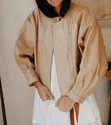 Campera marrón de cuero con cierre frontal, corte oversize, mangas abullonadas y puños ajustados.