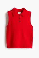 Chaleco corto de punto rojo vibrante, con cuello camisero y tapeta de tres botones oscuros. Presenta un tejido suave y ligeramente texturado, con ribetes acanalados en las sisas y el bajo.