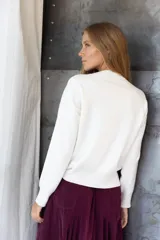 Buzo de punto color blanco, de corte holgado, cuello redondo y mangas largas con puños ajustados.