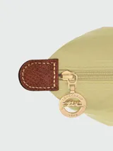 Mochila de diseño minimalista en color beige, con solapa y asa superior en cuero marrón texturizado. Cuenta con correas ajustables en color marrón y cierre principal.