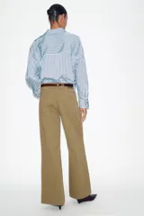 Jeans de tiro alto color azul oscuro, con cinco bolsillos, pernera ancha y nervio marcado en el delantero. Incluye un cinturón fino de cuero sintético marrón con textura de cocodrilo. Cierre frontal con cremallera y botón.