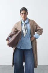 Cardigan de tejido de punto gris, con silueta larga, frente abierto, solapas clásicas y bolsillos aplicados en los laterales.