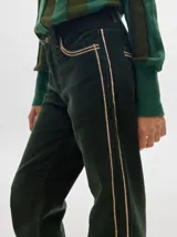 Pantalón de pana roja con corte holgado y tiro medio. Presenta una línea dorada a lo largo de la pierna.