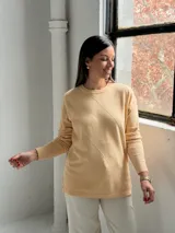 Sweater de punto color manteca con diseño de rombos en relieve, cuello redondo y mangas largas con puños ajustados.