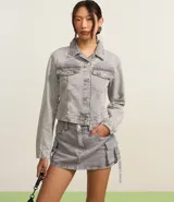 Campera corta de jean color negro con cuello inglés, abotonadura frontal, bolsillos tipo parche con solapa en el pecho y mangas largas.