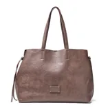 Cartera tipo shopper de gran tamaño, confeccionada en símil cuero con textura granulada. Cuenta con doble asa larga para hombro, cierre de cordones laterales y placa metálica con logo en la parte frontal.