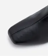 Bota de caña corta color negro, confeccionada en material sintético, con taco mediano bloque y puntera cuadrada.