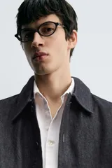 Sobrecamisa de denim oscuro, corte relajado, con cuello solapa, manga larga y cierre frontal de botones. Presenta bolsillos de vivo en la cadera.