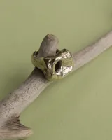 Anillo dorado con forma irregular y un agujero en el centro.