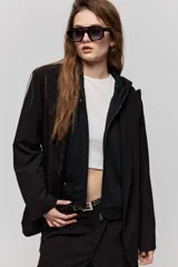 Blazer sastrero negro de calce relajado, con solapa clásica, cierre de un botón frontal y bolsillos laterales con tapa.