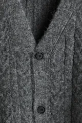 Saco gris de punto trenzado con escote en V pronunciado y botones frontales. Presenta remate acanalado en cuello, tapeta, puños y bajo. Corte holgado.