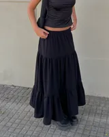Pollera larga negra de corte acampanado con diseño de volados escalonados y cintura elástica.