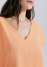 Blusa color naranja de lino con escote en V y mangas cortas.
