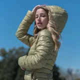 Campera puffer ultraliviana color verde militar con capucha ajustable, cierre frontal y bolsillos laterales con cierre.