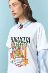 Remera blanca de algodón con estampa frontal colorida de un almacén tradicional. Posee cuello redondo y mangas cortas.