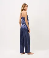 Pijama largo de satén azul con estampa de lunares, compuesto por una musculosa de escote en U con breteles finos y un pantalón de pierna recta con cintura elastizada.