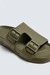 Sandalia tipo slide de goma, color verde militar, con dos tiras anchas ajustables mediante hebillas cuadradas. Presenta plantilla anatómica y suela gruesa con relieve.