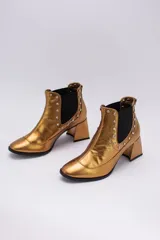 Botas cortas negras de cuero con elásticos laterales, taco cuadrado y apliques de tachas plateadas.