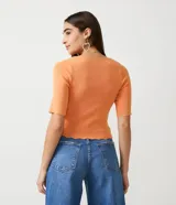 Blusa de punto acanalado color naranja, con escote cuadrado y mangas cortas con volados en los puños.