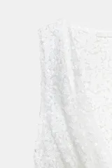 Top blanco sin mangas con escote drapeado y lentejuelas.