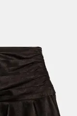 Falda corta de tiro bajo con diseño de volantes en el ruedo y detalle fruncido en la cintura. Confeccionada en tejido con efecto ante, cuenta con cierre lateral mediante cremallera oculta.
