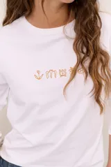 Remera blanca de manga larga con cuello redondo y diseño bordado en el pecho.