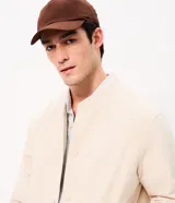 Campera bomber masculina de terciopelo cotelé color beige, con cuello redondo, mangas largas, cierre frontal de botones forrados, bolsillos laterales y terminaciones de elástico en puños y cintura.