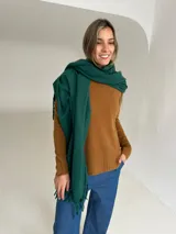Ruana de tejido de punto en color verde esmeralda, con diseño envolvente y flecos en los extremos.