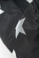 Cartera negra con diseño de estrellas plateadas brillantes. Tiene un asa ancha para llevar al hombro.