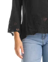 Blusa de rayón color marrón con escote en V, mangas tres cuartos acampanadas y ruedo asimétrico. Presenta detalles de bordado suizo y calados florales en puños y ruedo, con terminación festoneada.
