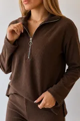 Sweater de tejido acanalado color marrón chocolate, con cuello polo y cierre frontal metálico. Presenta mangas largas y diseño con tajos laterales en el ruedo.