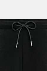 Pantalón flare de tiro medio, color azul, confeccionado en tejido de punto elástico. Cuenta con cintura elástica ajustable con cordón, bolsillos delanteros y corte amplio en las piernas.