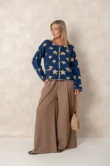 Saco abotonado de punto con diseño de estrellas en contraste, cuello redondo, mangas largas y dos bolsillos frontales. Presenta bordes con terminación enrollada.