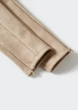 Leggings de efecto gamuza en color beige, con diseño ajustado, costuras frontales verticales y cierre lateral en el bajo.