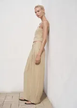 Pantalón Deia de corte recto y largo, color beige, con detalle de pinzas, trabillas y bolsillos laterales. Cuenta con cierre oculto de botón, gancho y cremallera, y forro interior.