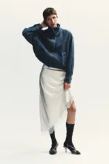 Falda midi de satén color blanco, de corte asimétrico y con encaje en el ruedo.