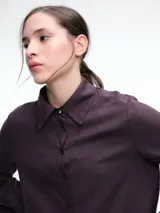 Camisa de corte oversize color bordó, con cuello clásico, cierre frontal de botones y mangas largas amplias con puños anchos. Presenta un diseño de caída fluida con bajo redondeado y levemente más largo en la parte posterior.