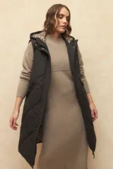 Chaleco largo marrón capitoneado con capucha, cierre frontal y bolsillos laterales. Forro interno de satén con estampado animal print.