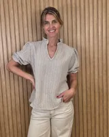 Blusa a rayas beige y blancas, con cuello en V adornado con volados y mangas cortas abullonadas.